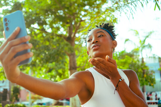 African woman sending kiss using digital device outdoors