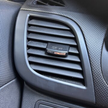 Hand opening a car air vent by sliding the airflow control 