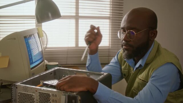 African American man repairing desktop computer with screwdriver, looking frustrated and rubbing forehead. Footage is perfect for IT support or hardware repair marketing