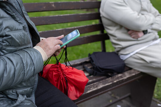 Woman sitting on a bench in a park with phone near a man.