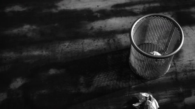 discarding failed ideas by throwing crumpled papers into a bin in dramatic black and white