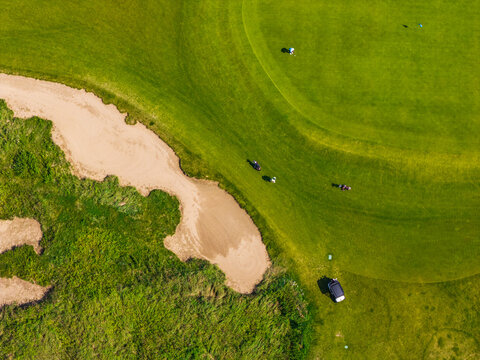 Aerial view of Sand Valley Golf Resort featuring lush green fairways, sand bunkers, and golfers playing on the course in Paslek, Warminsko-Mazurskie, Poland.
