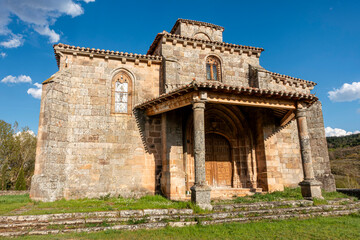 Obraz premium Exterior view of the 16th century Gothic church of San Martin de Tours, preserving a 12th century Romanesque bell tower, featuring a stone porch and pointed arch entrance, in Jaramillo Quemado, Burgos