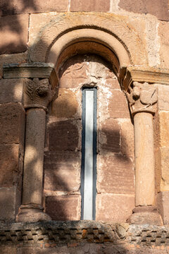 12th century Romanesque apsidal window with round arch, carved capitals, and columns on the stone wall of San Martin de Tours church, located in Vizcainos, Burgos, Castilla y Leon, Spain