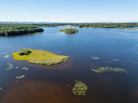 Aerial view of the Oulujoki river delta featuring lush green islands, calm dark water, and dense forest along the banks in Oulu, North Ostrobothnia, Finland.