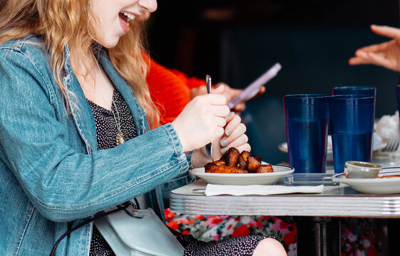 Unrecognizable Woman Enjoying a Meal with Friends at a Casual Restaurant