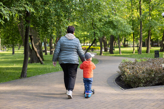 Grandmother taking grandson for a walk on a scooter.