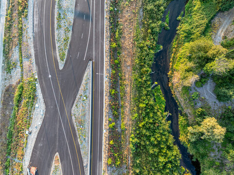 Aerial view of Interurban South Trailhead featuring a paved road alongside a winding stream and lush green vegetation in Fife, Washington, United States.