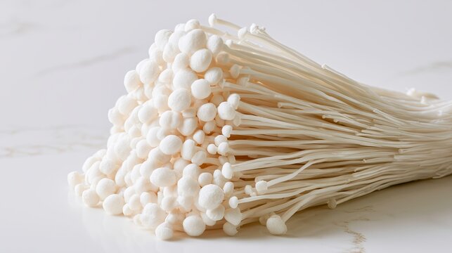 Enoki mushrooms clustered on white marble surface  