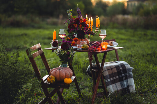 Fall table decoration with pumpkin composition. Family cozy thanksgiving dinner arrangement outdoors, in a garden, elegant wedding decor. Countryside style, rose wine, cheeseboard, fruits, autumn mood