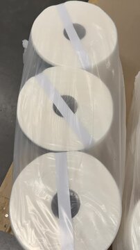 Household paper towels are stacked in sealed packages, creating an organized retail display that offers convenient access to everyday cleaning and kitchen essentials. Close up.