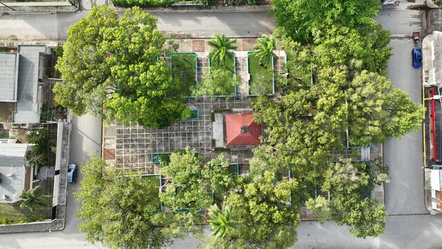 Aerial view of the central park with a red-roofed gazebo, tiled walkways, and lush trees surrounded by urban streets in Sabana de la Mar, Hato Mayor Province, Dominican Republic.