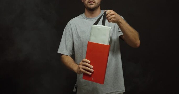 Person removing a fire blanket from its wall-mounted case in a lightly smoke-filled room. Ideal for fire safety, emergency preparedness, firefighting equipment, and workplace safety training.