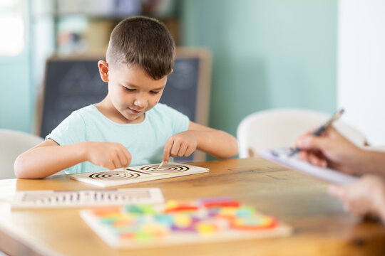 Child psychologist asks boy to play game: using both hands to simultaneously navigate maze drawn on a board