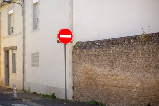 Urban street scene with no entry sign near historic stone wall