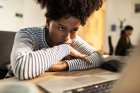 Tired young woman leaning on desk in modern office