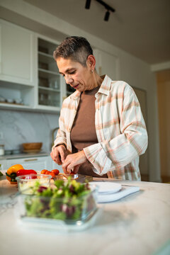 Older adult chopping fresh vegetables in home kitchen