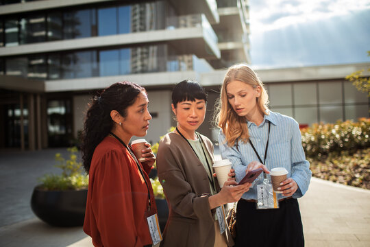 Three colleagues with visitor badges networking outside office