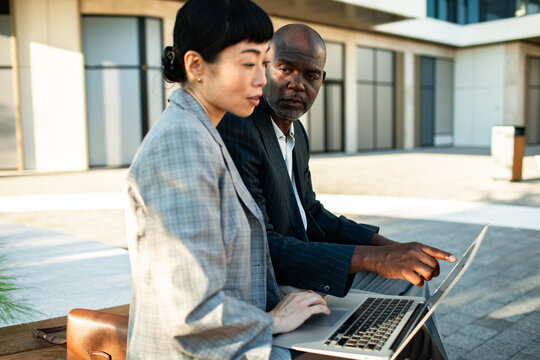 Two business colleagues reviewing laptop outside office