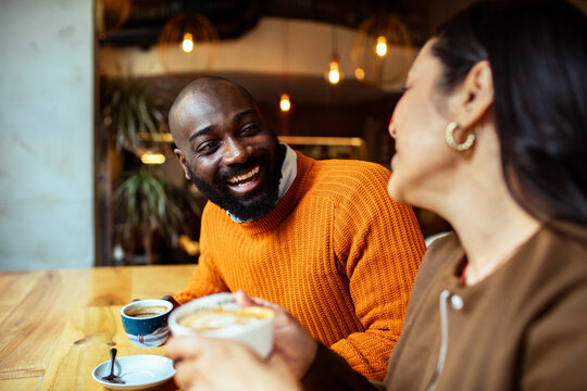 Smiling friends drinking coffee at cozy cafe