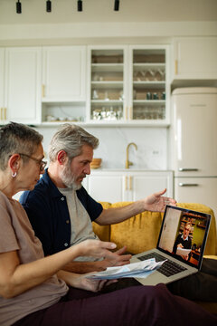 Senior couple discussing bills on video call with advisor at home