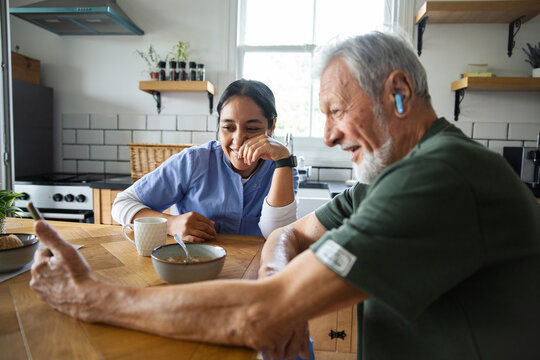 Caregiver and senior using smartphone in home kitchen