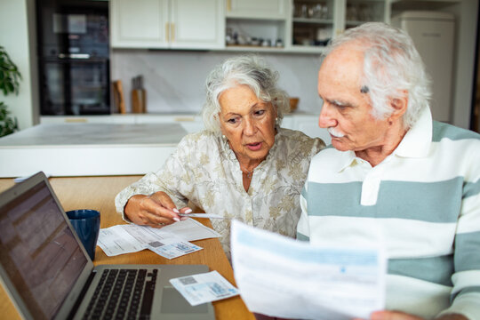Senior couple reviewing bills at kitchen table
