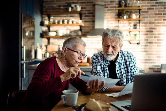 Senior couple reviewing bills at home kitchen table