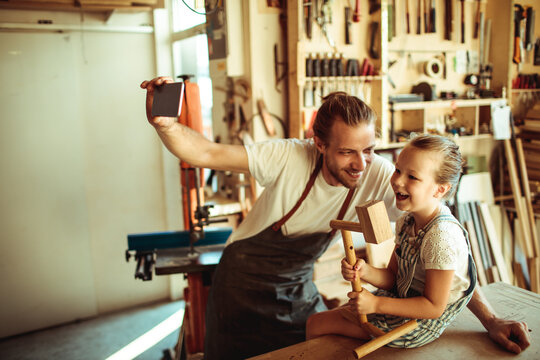 Father and daughter taking selfie in home woodshop