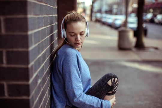 Young woman listening to music on city sidewalk