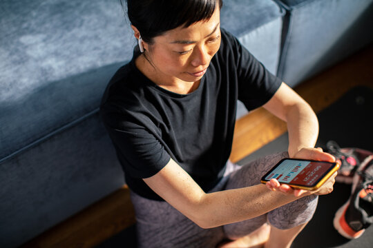 Woman checking fitness app at home after workout
