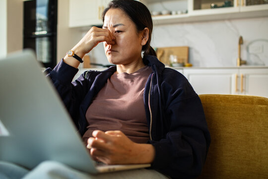 Woman with laptop feeling stressed at home
