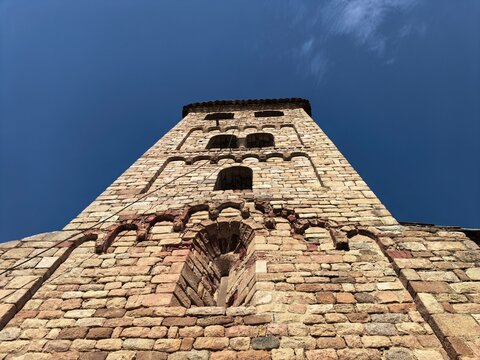Low-angle shot of a church tower reaching up into a bright blue sky, majestic and serene.