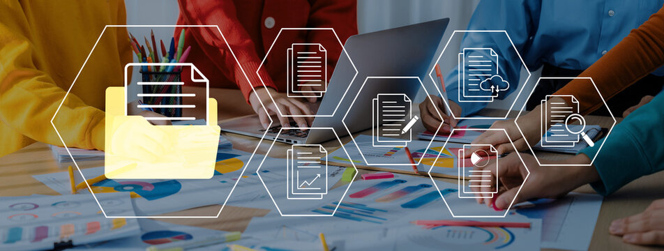 Team Collaborating on Project Documents with Laptops and Creative Graphics in a Bright Office Environment. Glyphic.