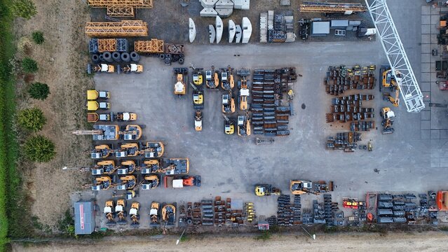 Aerial view of Iron Mountain Data Centers FRA-2 construction equipment yard with rows of excavators, cranes, and heavy machinery on a gravel lot in Frankfurt am Main, Hessen, Germany.