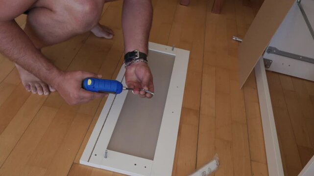 Man assembling flat pack furniture using a power screwdriver