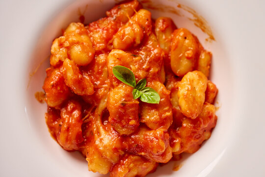 Gnocchi covered with tomato sauce and served on plate with fresh basil garnish