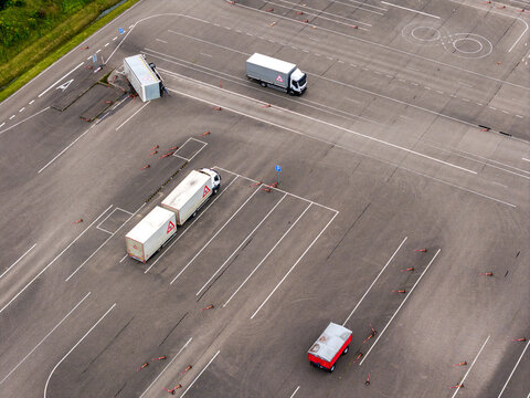 Aerial view of a driving training ground with several trucks maneuvering on asphalt, marked with white lines and cones in Vilnius, Vilniaus apskritis, Lithuania.