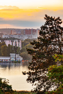 Vertical cityscape of residential apartment buildings near a lake and park at sunset