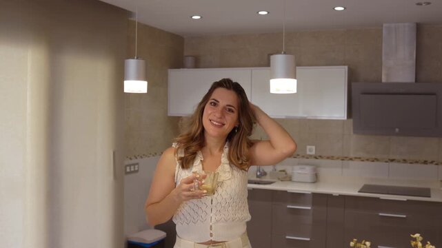 Beautiful smiling woman drinking coffee in a modern kitchen