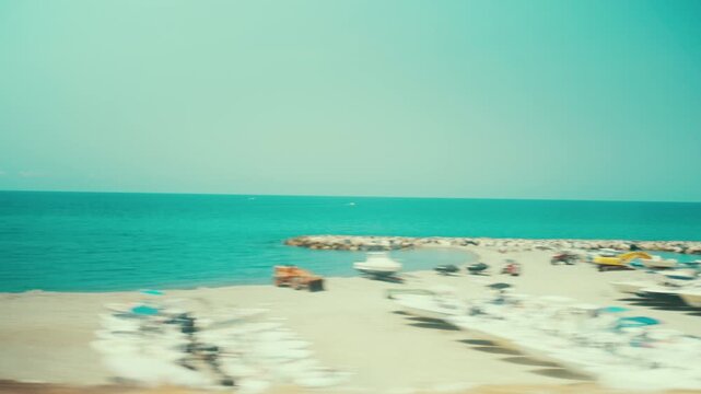 The sea in Calabria and a beach with bathers, seen from the window of a train