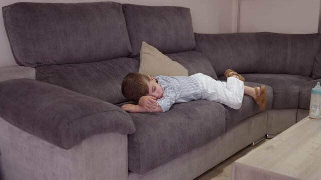 Sleepy little boy falling asleep on a comfortable living room sofa