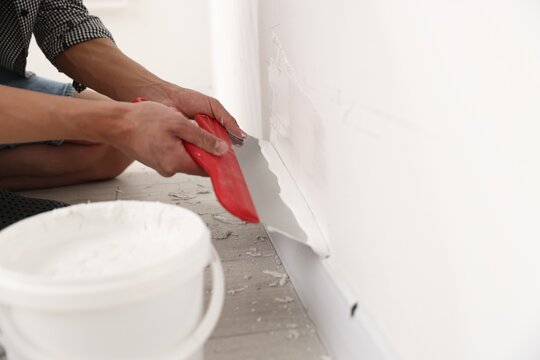 Worker plastering white wall with putty knife indoors, closeup. Space for text