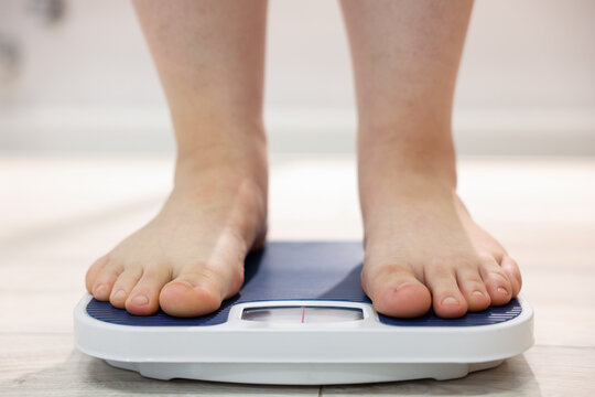 Overweight woman on scale at home, closeup