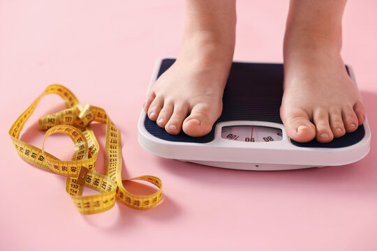 Overweight woman on scale and measuring tape against pink background, closeup
