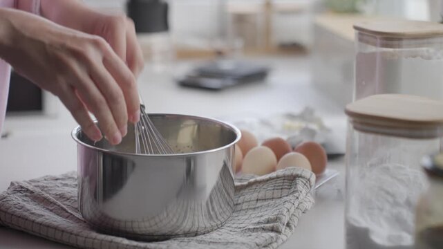 Butter pieces are added to saucepan with whisk on kitchen counter
