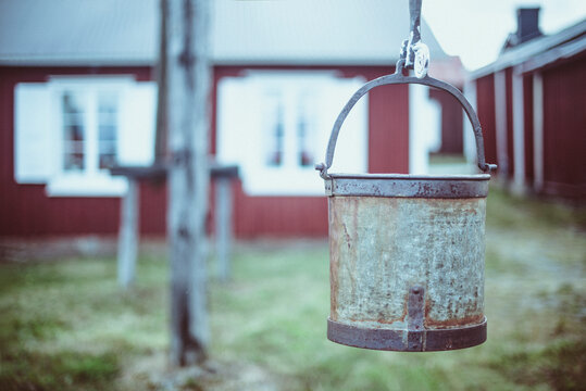 Close-up of an old Metal bucket hanging in a garden with houses in the background, Gammelstaden, Lulea, Norrbotten, Sweden