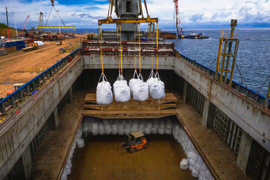 Overhead view of merchandise hanging on a crane being loaded into a ship's hold, Indonesia