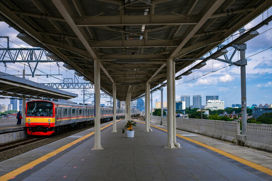 Distant rear view of a woman standing on the platform at Manggarai Train Station, Jakarta, Indonesia