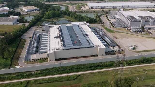 Aerial view of large data center facility with rooftop cooling units and surrounding industrial infrastructure in Illinois, United States.